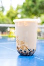 a cup of iced milktea with tapiocas and guiling jelly on a pingpong table vertical composition