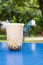 cup of iced milktea with tapiocas and guiling jelly on pingpong table vertical composition