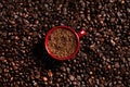 Cup with instant coffee on roasted beans, top view Royalty Free Stock Photo