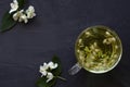 Cup of Jasmine tea. Cup of hot herbal tea with jasmine fresh flowers on a black table Royalty Free Stock Photo