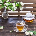 Cup of jasmine tea and transparent tea pot on the wooden table. Spring tea party. Copy space Royalty Free Stock Photo