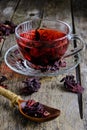 Cup karkade tea with bright red shade wooden background