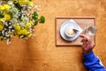 A cup of latte coffee hand with spoon of fresh flowers Royalty Free Stock Photo