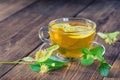 Cup of lime tea, standing on a wooden table, surrounded by fragrant linden flowers Royalty Free Stock Photo