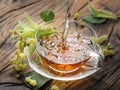 Cup of linden tea and lime flowers on the wooden table