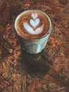 Piccolo latte. heart latte art coffee in Glass on the vintage wooden table.