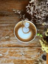 Heart latte art coffee in white cup on the vintage wooden table and dried flower foreground. Royalty Free Stock Photo