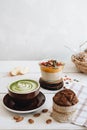 The cup of matcha tea with almond milk , mango pudding and banana muffin at the white table