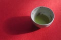 Cup of matcha tea on red background