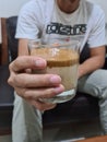 A cup of mik dalgona coffee foam holding by a man