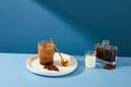 A cup of milk coffee is placed on a ceramic plate with a metal spoon and coffee beans, a cup of milk and a bottle of black coffee Royalty Free Stock Photo