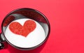 Cup of milk with decorative heart on red background, concept of valentine day Royalty Free Stock Photo