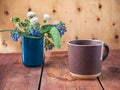 A cup of morning waffle in a large brown mug and a spring bouquet, dandelions and Symphytum caucasicum