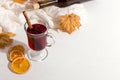 A cup of mulled wine with spices, bottle, a scarf, dry leaves and oranges on the table. Autumn mood, a method to keep warm in the