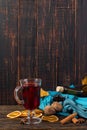 Cup of mulled wine with spices, bottle, scarf, dry leaves and oranges on a wooden table. Autumn mood, method to keep warm in the