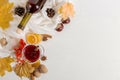 A cup of mulled wine with spices, bottle, scarf, spices, dry leaves and oranges on the table. Autumn mood, method to keep warm in