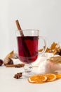 A cup of mulled wine with spices, scarf, spices, dry leaves and oranges on the table. Autumn mood, a method to keep warm in the