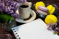 An even row of multicolored macaroons, a small alarm clock, a cup of coffee and a notebook on a wooden background. Royalty Free Stock Photo