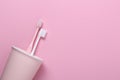 Cup with pink and white toothbrushes on pink background.Taking care of teeth, dental concept. Flat lay photo, copy space, top view