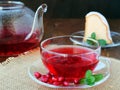 Cup of pomegranate tea with mint and tea pot with a piece of cake Royalty Free Stock Photo