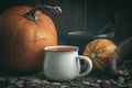 Cup of pumpkin juice, pumpkins, canvas sack of pumpkins seeds and mortar on wooden table.