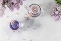 Cup of purple tea with lemon, teapot and bouquet of blooming lilac on light background. Spring tea drinking. Greeting card,