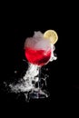 A cup of red cold cocktail with dry ice smoke and a lemon slice Royalty Free Stock Photo