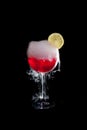 A cup of red cold cocktail with dry ice smoke and a lemon slice Royalty Free Stock Photo