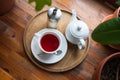 Cup with red fruit tea, teapot and sugar bottle on round wooden tray on wood table, cafe. Top view, flat lay Royalty Free Stock Photo