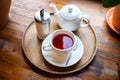 Cup with red fruit tea, teapot and sugar bottle on round wooden tray on wooden window sill, cafe. Top view, close-up Royalty Free Stock Photo