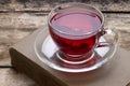 Cup of red karkade tea with book on wood background Royalty Free Stock Photo