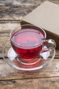 Cup of red karkade tea with book on wood background Royalty Free Stock Photo