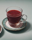 A cup of red liquid sits on a green plate Royalty Free Stock Photo