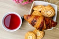 A cup of rose tea. Croissant and biscuits on a plate. Pink flowers. Royalty Free Stock Photo