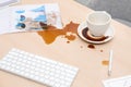 Cup with saucer and coffee spill on wooden office desk Royalty Free Stock Photo