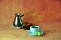 A cup on a saucer with hot coffee, an old-fashioned copper turk and coffee beans on a brown background. Close up shot Royalty Free Stock Photo