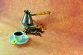 A cup on a saucer with hot coffee, an old-fashioned copper turk and coffee beans on a brown background. Close up shot Royalty Free Stock Photo