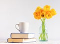 Cup stand on books and tulips on the table