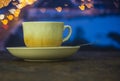 The Cup stands on a saucer with a colorful bokeh
