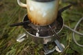 Cup of steel on fire. Tea on hike. Drink in woods. Cooking on gas burner Royalty Free Stock Photo