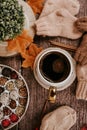 Cup of strong black coffee, autumn leaves and handmade woolen socks on wooden background