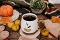 Cup of strong black coffee, autumn leaves and handmade woolen socks on wooden background