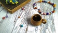 A cup of strong coffee,the vintage Christian Bible, Sacred writings, , and ceramic beads on a white wooden table.
