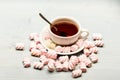 Cup and sweets prepared as dessert. Mug filled with black brewed tea, spoon and heap of marshmallow on white wooden Royalty Free Stock Photo