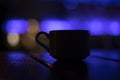 Cup on table in purple. Silhouette of cup in dark room. Mug with drink Royalty Free Stock Photo