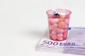 Cup with tabletts on stack of 500 Euro notes Royalty Free Stock Photo