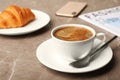 Cup of tasty aromatic coffee and croissant for breakfast