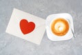 A cup of tasty cappucino and valentine letter with heart.