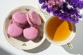 A cup of tea with almond cookies on a white background. Pink pasta and a mug. Flowers in a vase. Macaroons. A Cup of Tea.