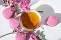 A cup of tea with almond cookies on a white background. Pink pasta and a mug. Flowers in a vase. Macaroons. A Cup of Tea.